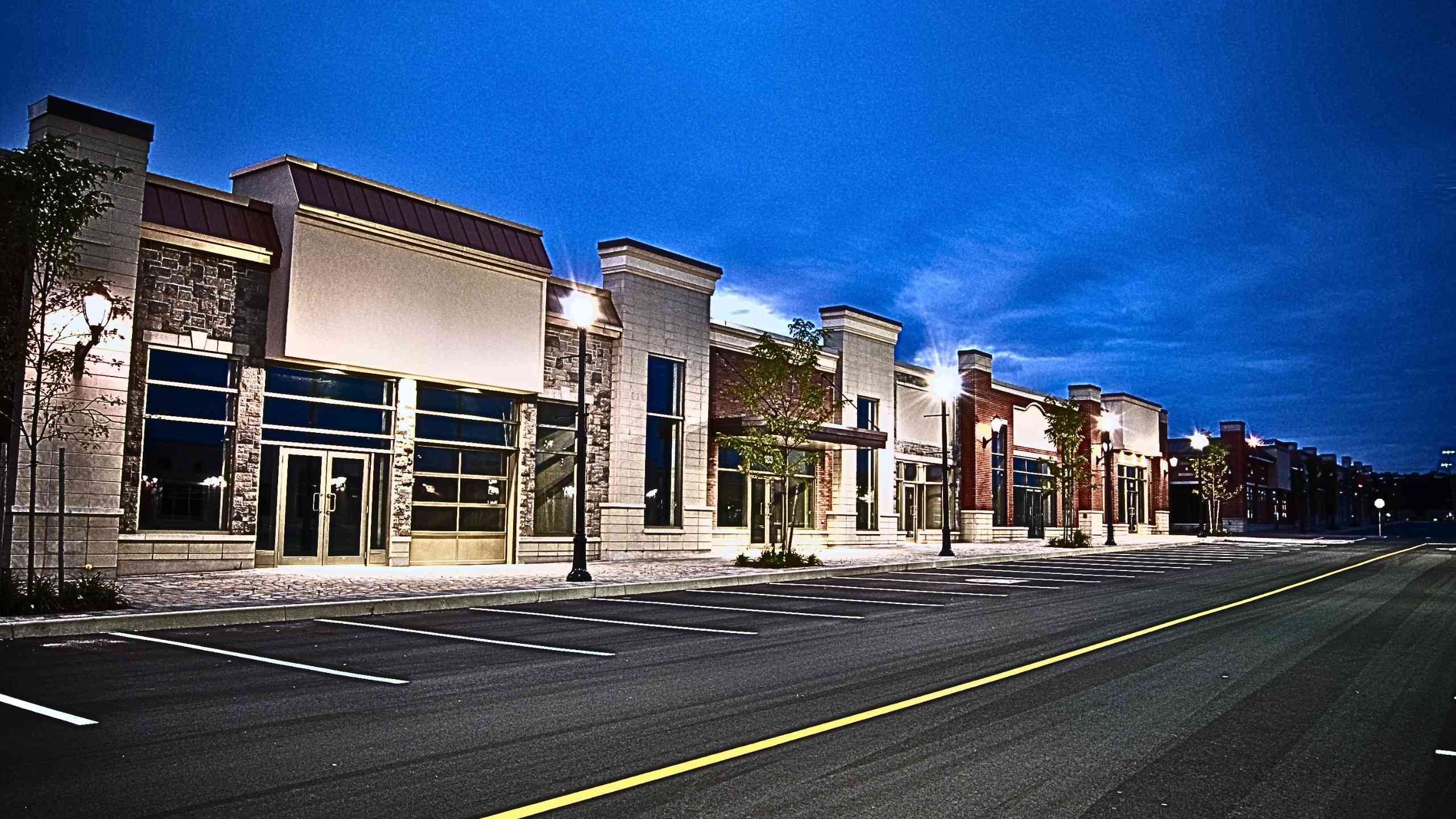 The image shows a row of empty stores of a strip mall.